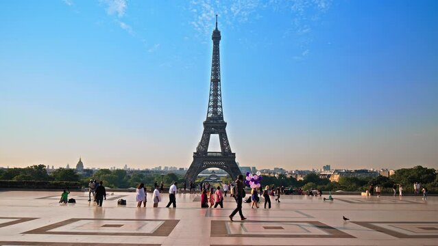 Views of the Tower from Trocadero in Paris, France. Tourists enjoy historical landmark and symbol of Paris taking pictures and celebrating with balloons at sunrise in Paris.