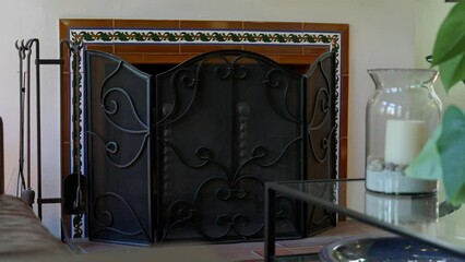 Stylish fireplace with metal fire guard screen and cleaning tools in living room. Cozy place for relaxation in modern home