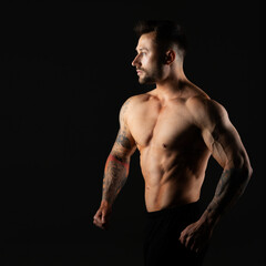 Fototapeta premium Man with bare muscular torso, studio photo on black background. Bodybuilder.