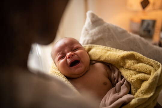Newborn baby crying in arms of mother