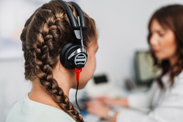 Audiologist doing impedance audiometry or diagnosis of hearing impairment. An beautiful teenage...