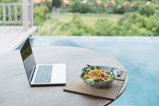 a laptop and a healthy vegetarian lunch bowl 