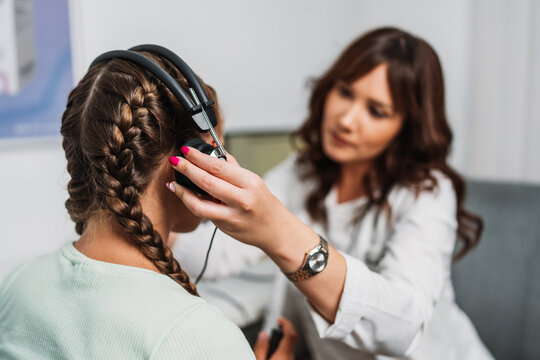 Audiologist doing impedance audiometry or diagnosis of hearing impairment. An beautiful teenage girl getting an auditory test at a hearing clinic. Healthcare and medicine concept.