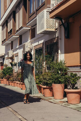 beautiful brunette girl in a green dress posing on the street of the old city. model posing on a summer sunny day.