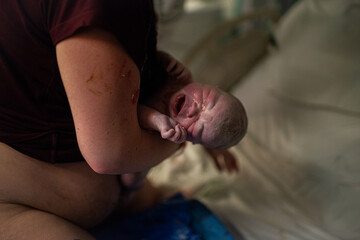 Crying baby being held by his mother after being born