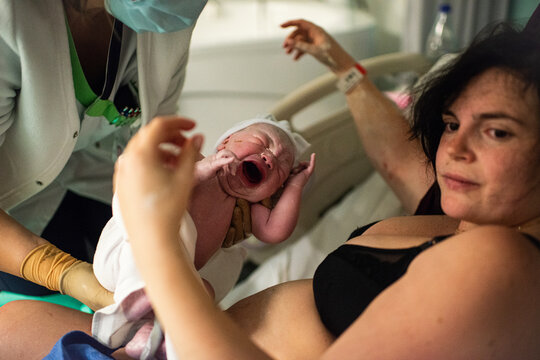 Midwife handing over newborn baby to mother