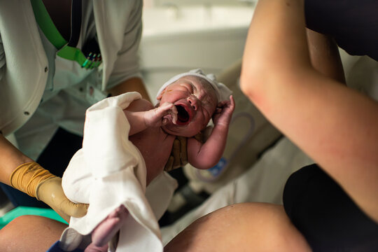 Midwife handing over newborn baby to mother