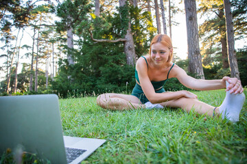 Obraz premium An athlete performs stretching exercises following online lessons with her laptop