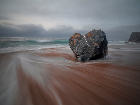 Long exposure of the flowing sea and a heart shaped rock on the Portizuelo beach, Asturias, Spain