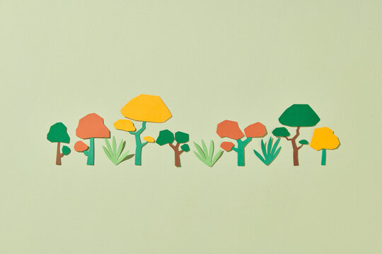 Colorful trees cut from paper on green pastel background