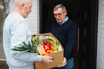 Caregiver delivering food at door of senior man
