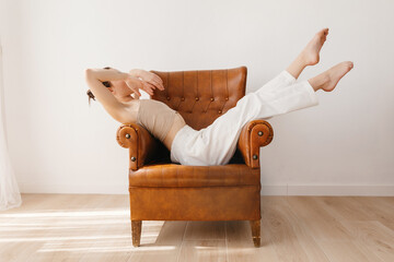 Carefree woman sitting on armchair in graceful pose