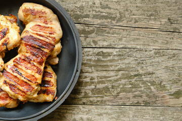 Chicken fillet steaks in a pan on a wooden table with space for text. Flat lay, copy space. Rustic background.