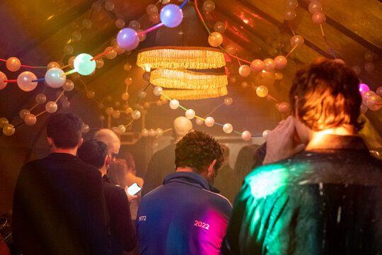 Friends having fun at indie alternative party lit by led string balls