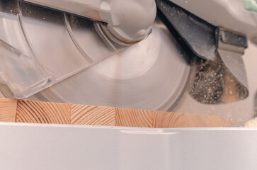 Carpentry machine. Sharp blade of a circular saw cuts a wooden board. High rotation speed.