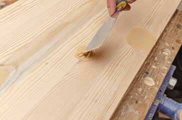 The process of puttying a wooden board. Spatula, putty, wooden board. Carpentry works.