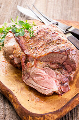 Traditional barbecued Greek lamb shoulder with with herb aund spice served as close-up on a wooden...