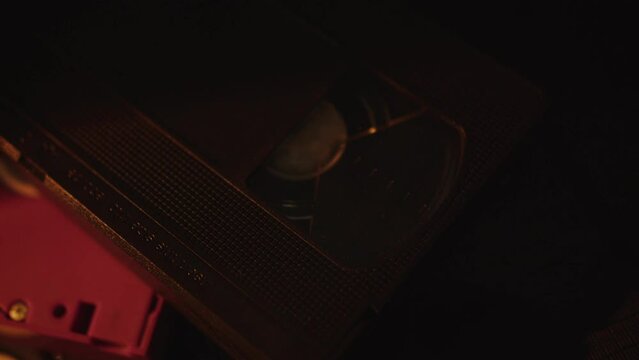a stack of old video cassettes in the dim light of a lamp