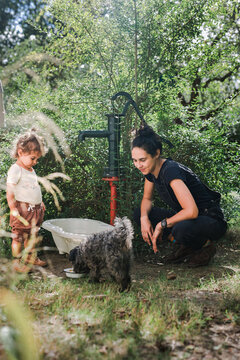 Mother Daughter and the dog Pumping Water in the tub in the Garden