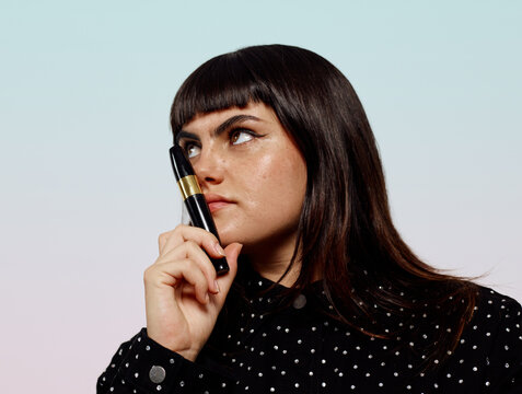 Woman with glowing skin holding make up product