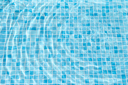 Minimal swimming pool with water and blue tiles background.