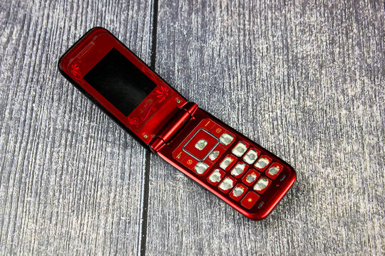 Classic mobile phone, flip.Retro folding cell phone. Old-fashioned push-button mobile wireless phone vintage.Folding phone with buttons. Old, dilapidated used phone, 2005-2010s. - Powered by Adobe