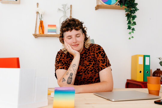 Smiling non binary queer at working desk