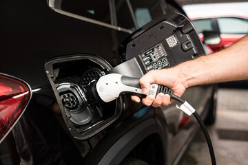 man charging his electric car in garage at home