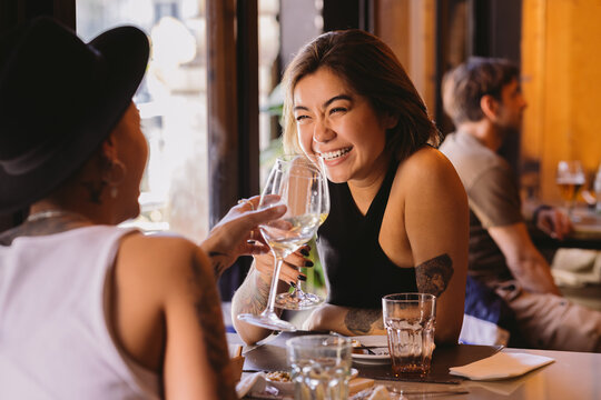 Happy asian woman toasting with her girlfriend in a restaurant