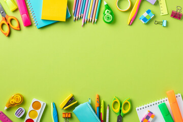 Frame of colorful school supplies on green background. Back to school concept.