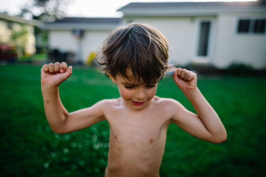 Preschool boy flexes in backyard