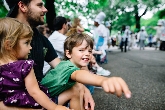 kids sit on dad's lap to watch parade
