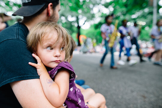 young girl clings to dad to watch parade