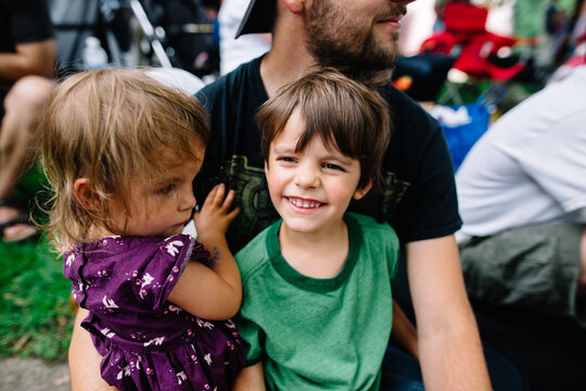 kids sit on dad's lap to watch parade