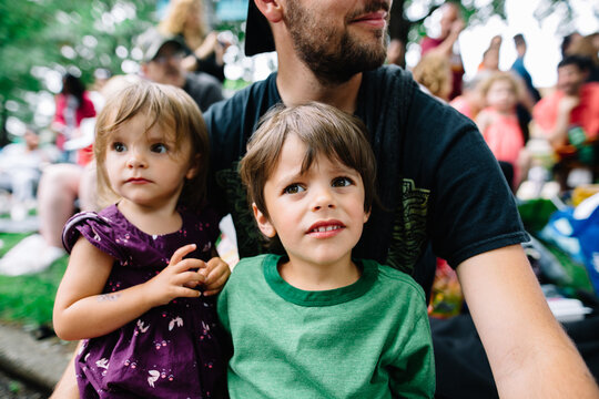 kids sit on dad's lap to watch parade