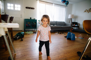 Portrait of toddler in living room surrounded by toys