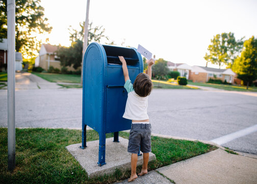 Young Boy Mails A Letter In Post Office Box