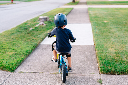 Young boy rides bike down sidewalk