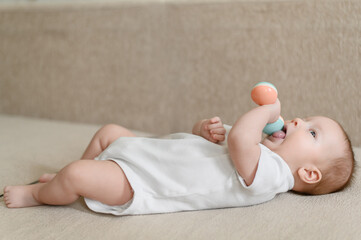 A cute baby plays,studies a rattle.A toy for the development of fine motor skills of the...