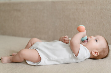 A cute baby plays,studies a rattle.A toy for the development of fine motor skills of the baby,visual,auditory sensations