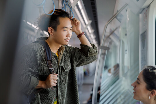 Woman with man holding hanging strap while traveling in a metro