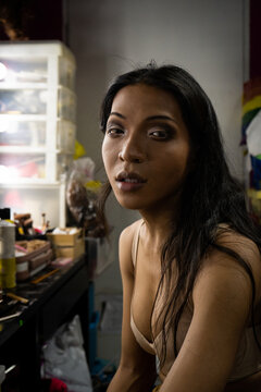 A drag performer poses for a portrait while doing makeup backstage