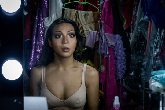 A model looks at herself in the mirror while doing drag queen makeup