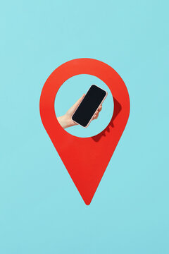 A hand holds a smartphone in location pin