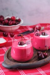 Cold cherry summer soup Meggyleves with cream and whole cherries in glass goblets on a table with a red tablecloth. Cold summer fruit soups.