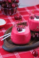 Cold cherry summer soup Meggyleves with cream and whole cherries in glass goblets on a table with a red tablecloth. Cold summer fruit soups.