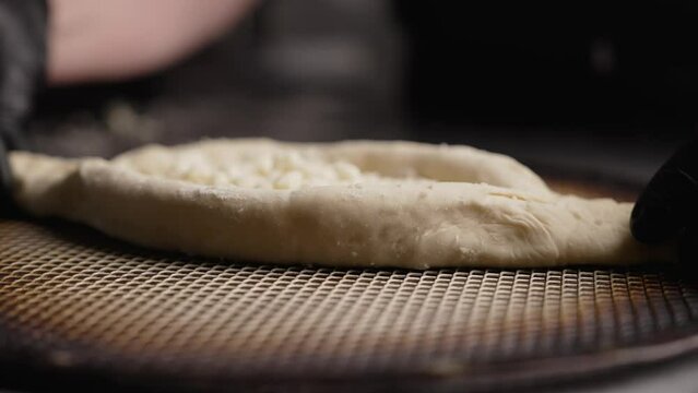 Kneading the dough, making the shape of the boat of khachapuri in adjaruli, close-up on the hands. Dough for khachapuri, in the form of khachapuri. Women's hands mold dough for khachapuri.