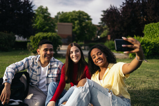 Multiracial group of students in the campus gardens taking selfies