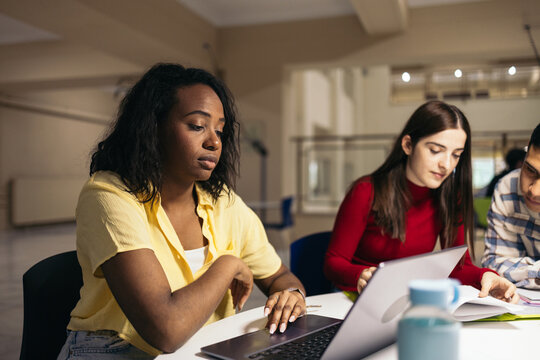 Students doing work and studying with laptops and notes in the college
