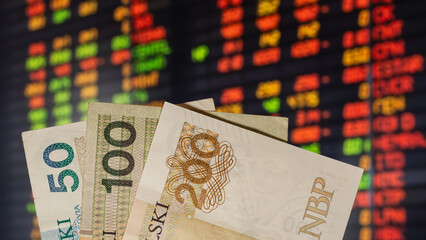 warsaw, poland - 05 07 2023: Polish banknotes PLN, in the background of the stock market on the computer display (selective sharpness)